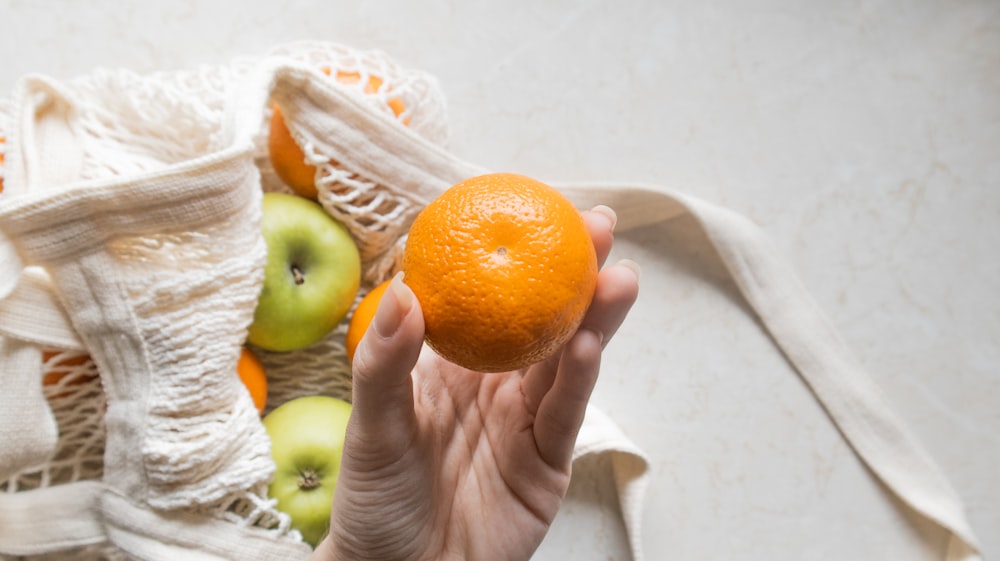 a person holding an orange in their hand