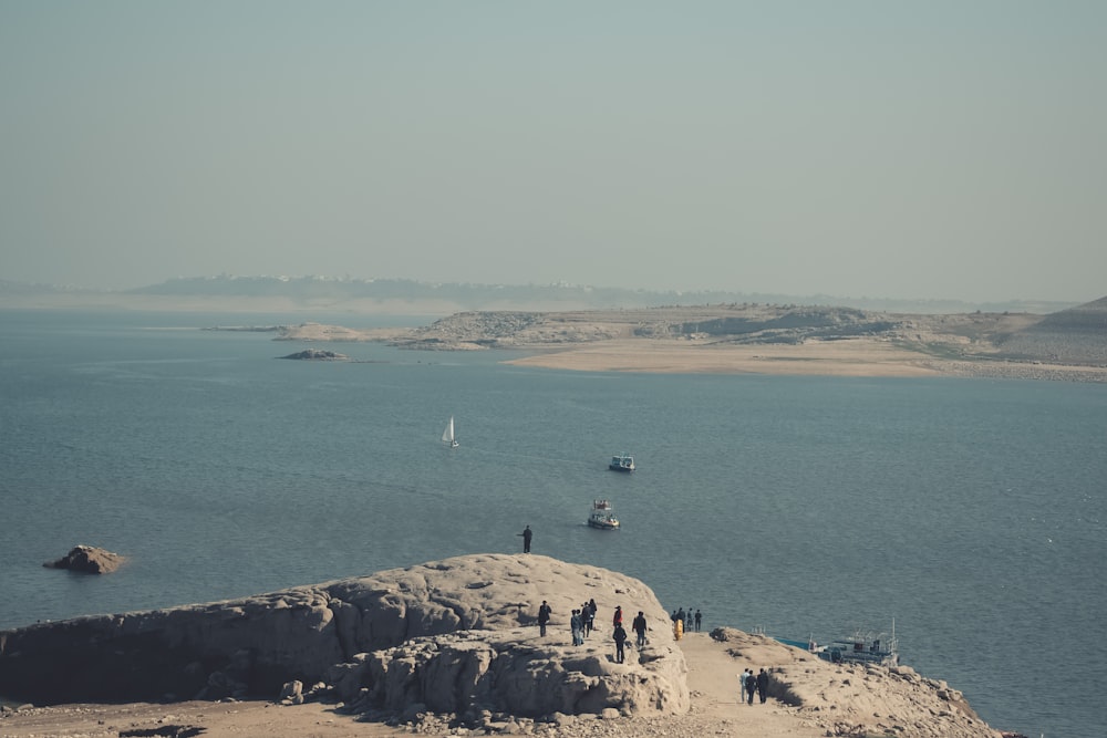 a group of people standing on top of a cliff near a body of water