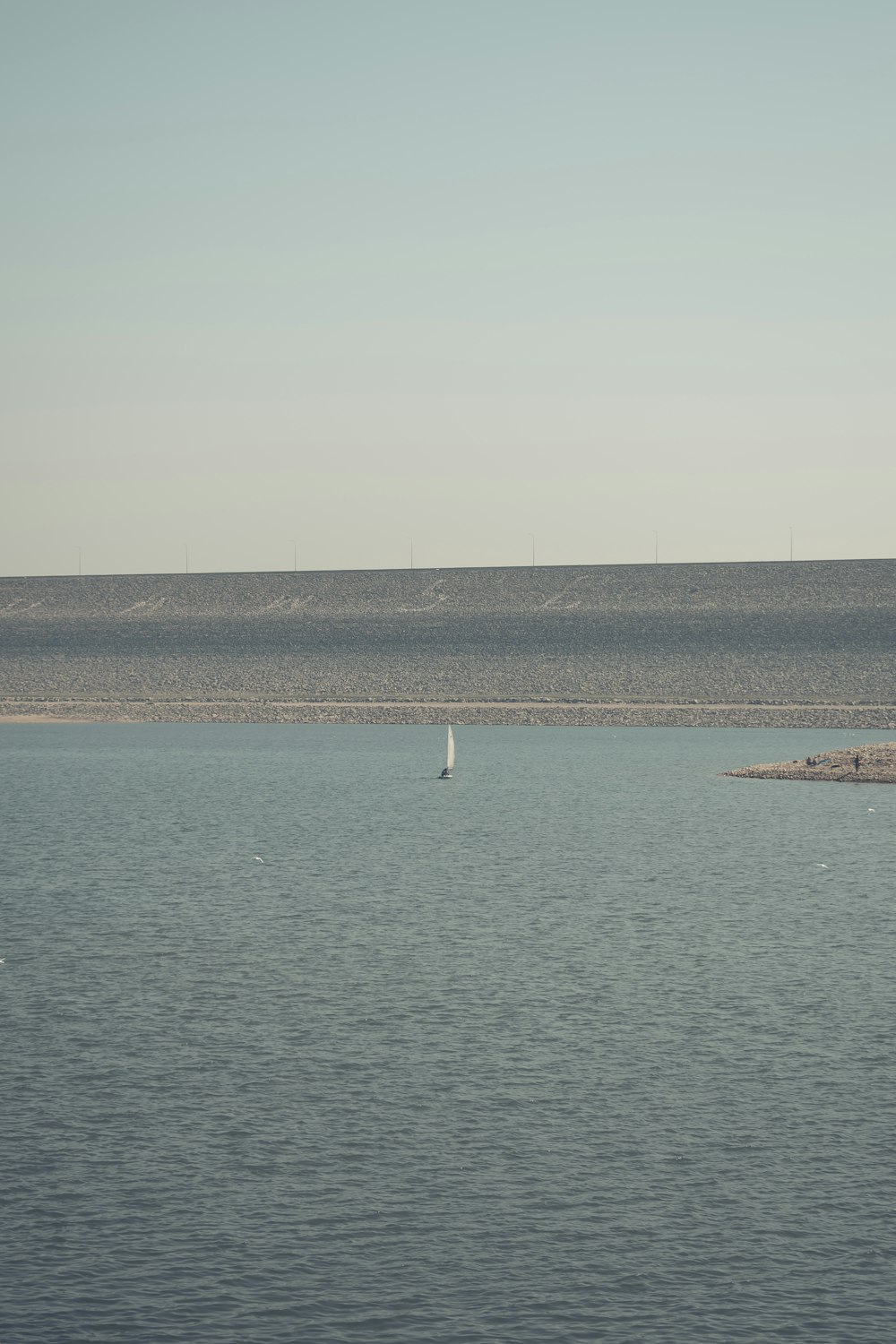 a lone sailboat in the middle of a large body of water