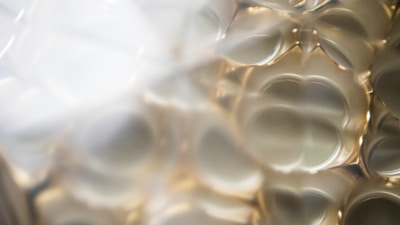 A macro close-up of transparent, curved glass surfaces with gentle reflections and refractions, creating an abstract pattern of light and shadow.