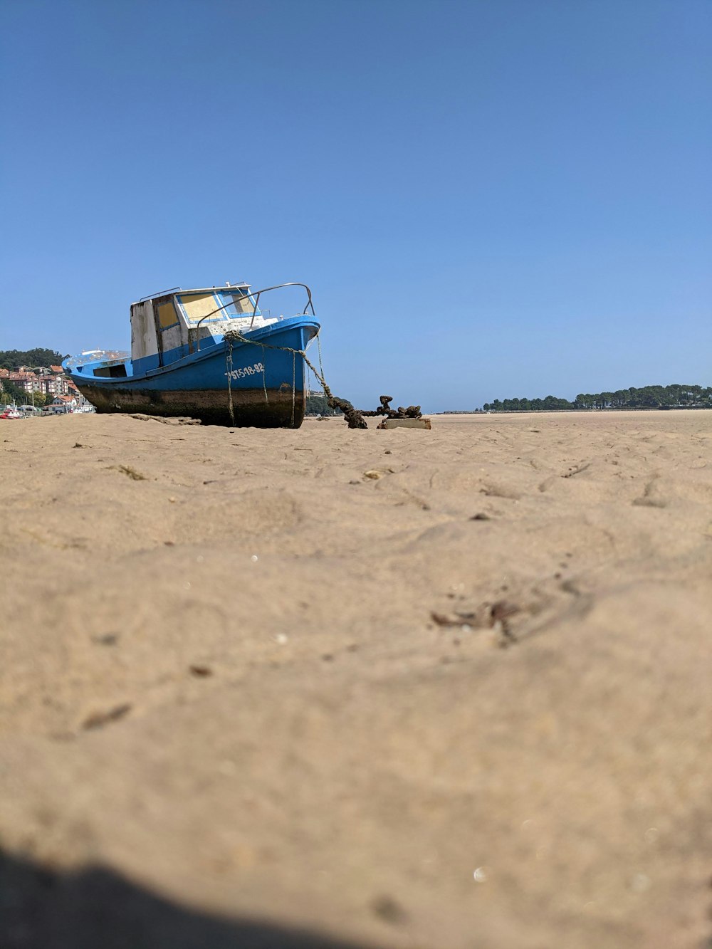 a blue boat sitting on top of a sandy beach