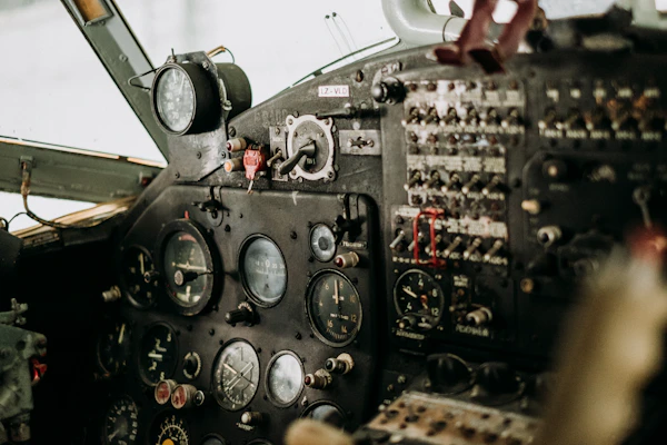 A close-up of a propeller plane’s cockpit, showcasing detailed instruments and controls.