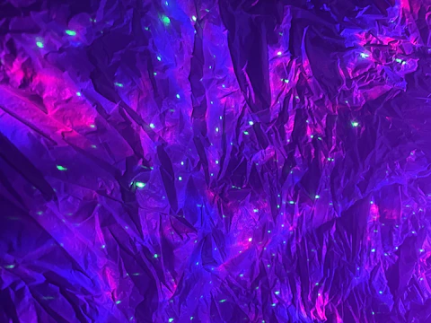 Microscopic texture resembling dark cosmic dust illuminated by a single violet spark.