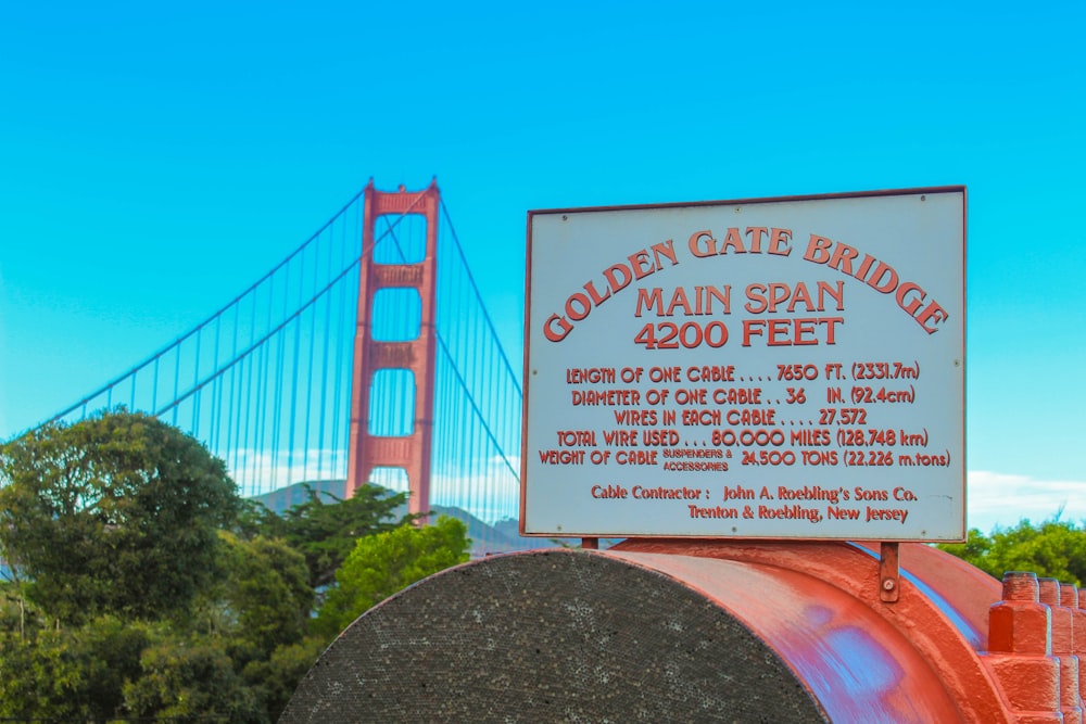 a sign on top of a red pipe near a bridge