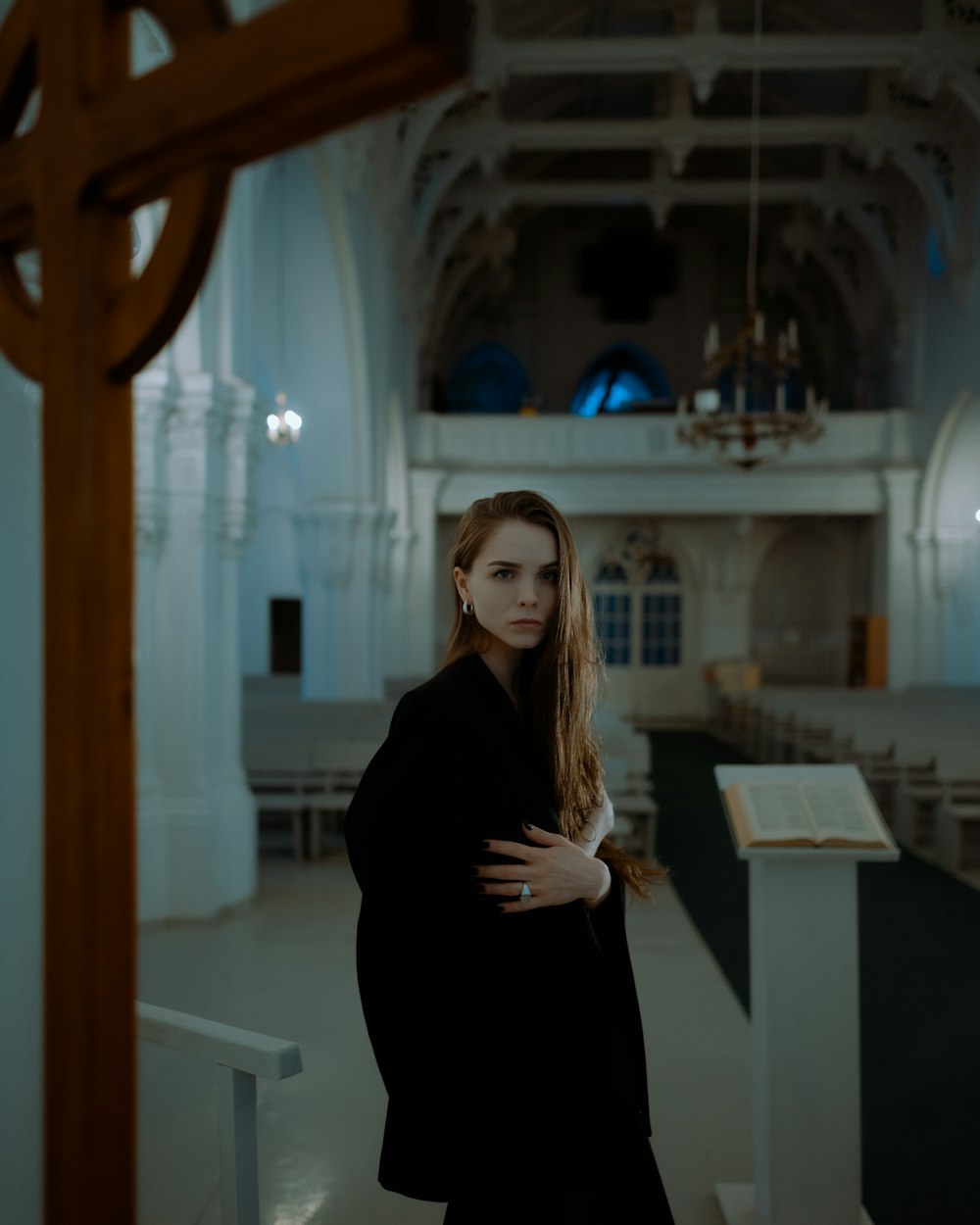 a woman standing in a church with her arms crossed