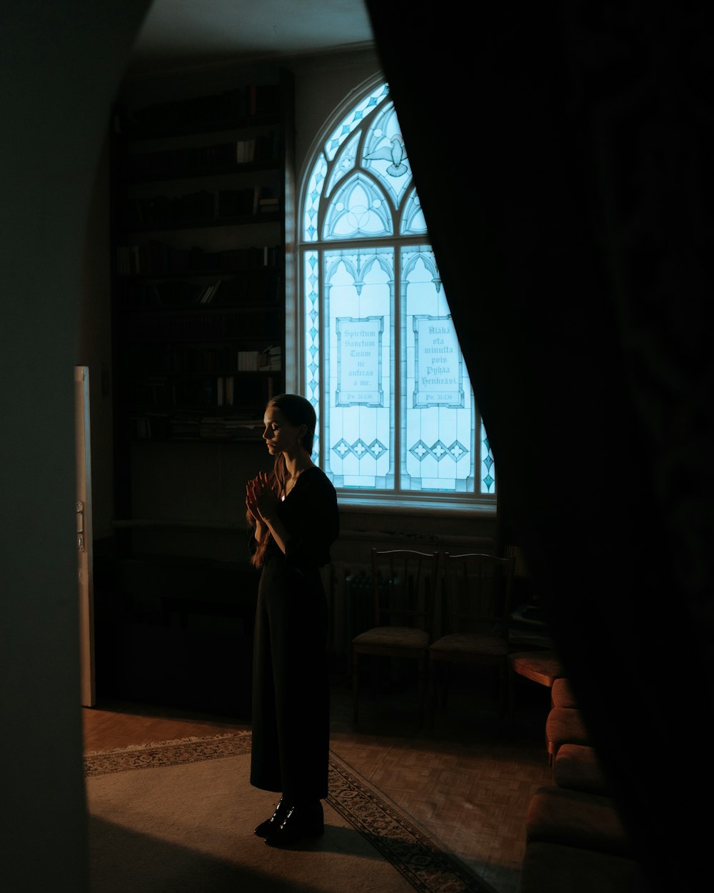 a woman standing in front of a window in a dark room