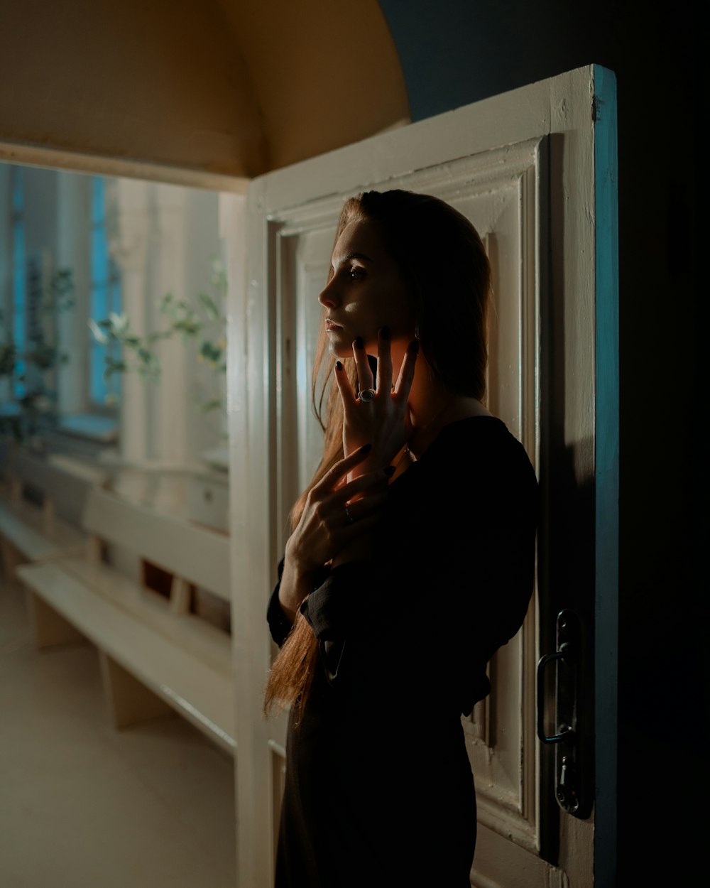 a woman standing in front of a door talking on a cell phone