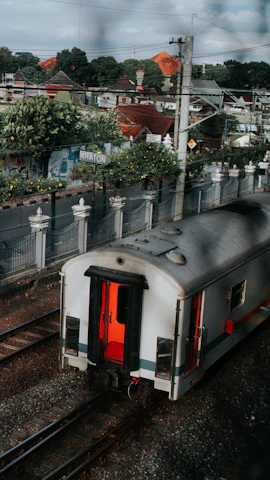 a train traveling down train tracks next to a lush green hillside