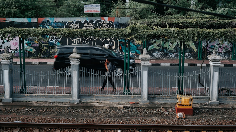 a car parked on the side of a road next to a fence