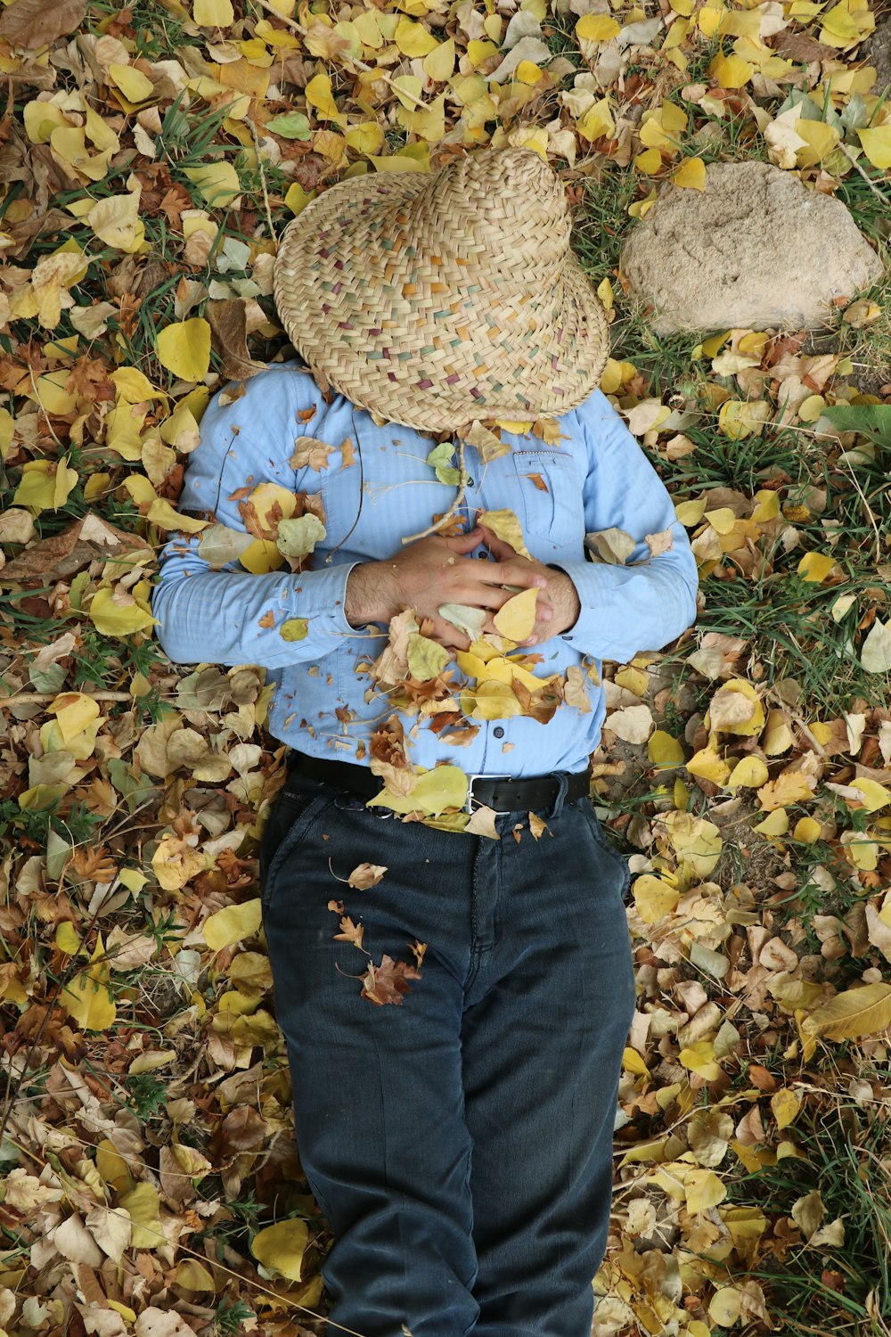 a person standing in leaves with a hat on