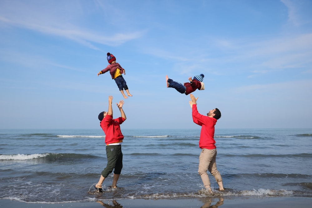 a group of people standing on top of a beach next to the ocean