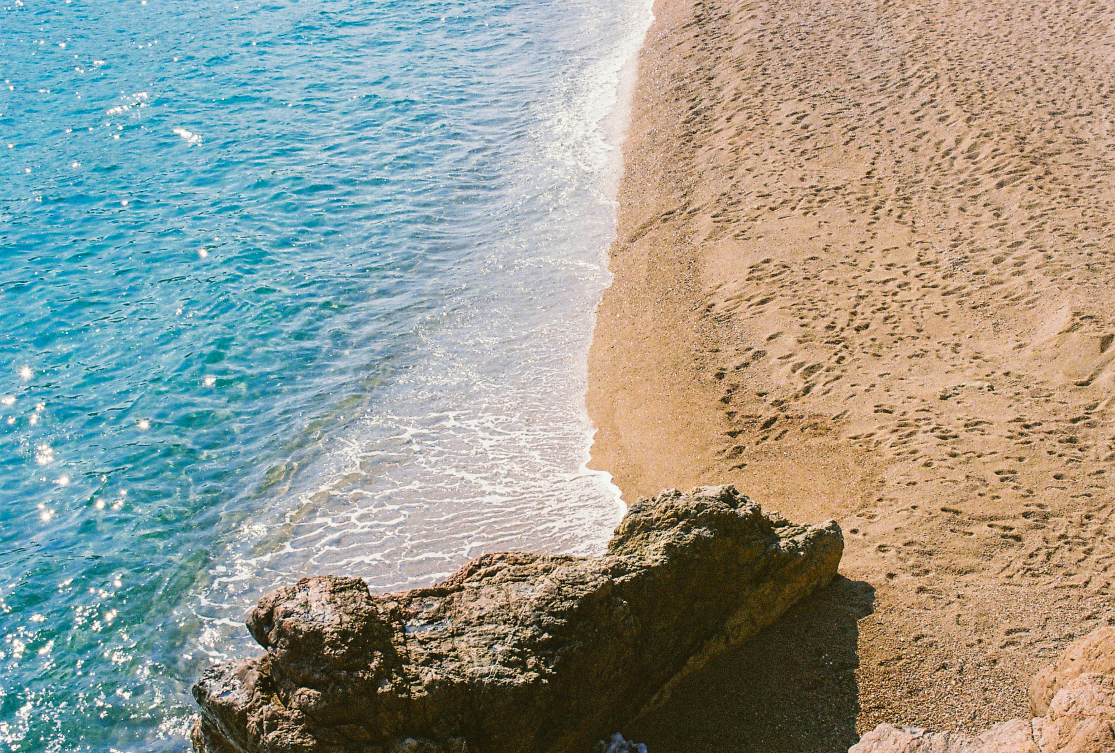 a couple of people standing on top of a sandy beach