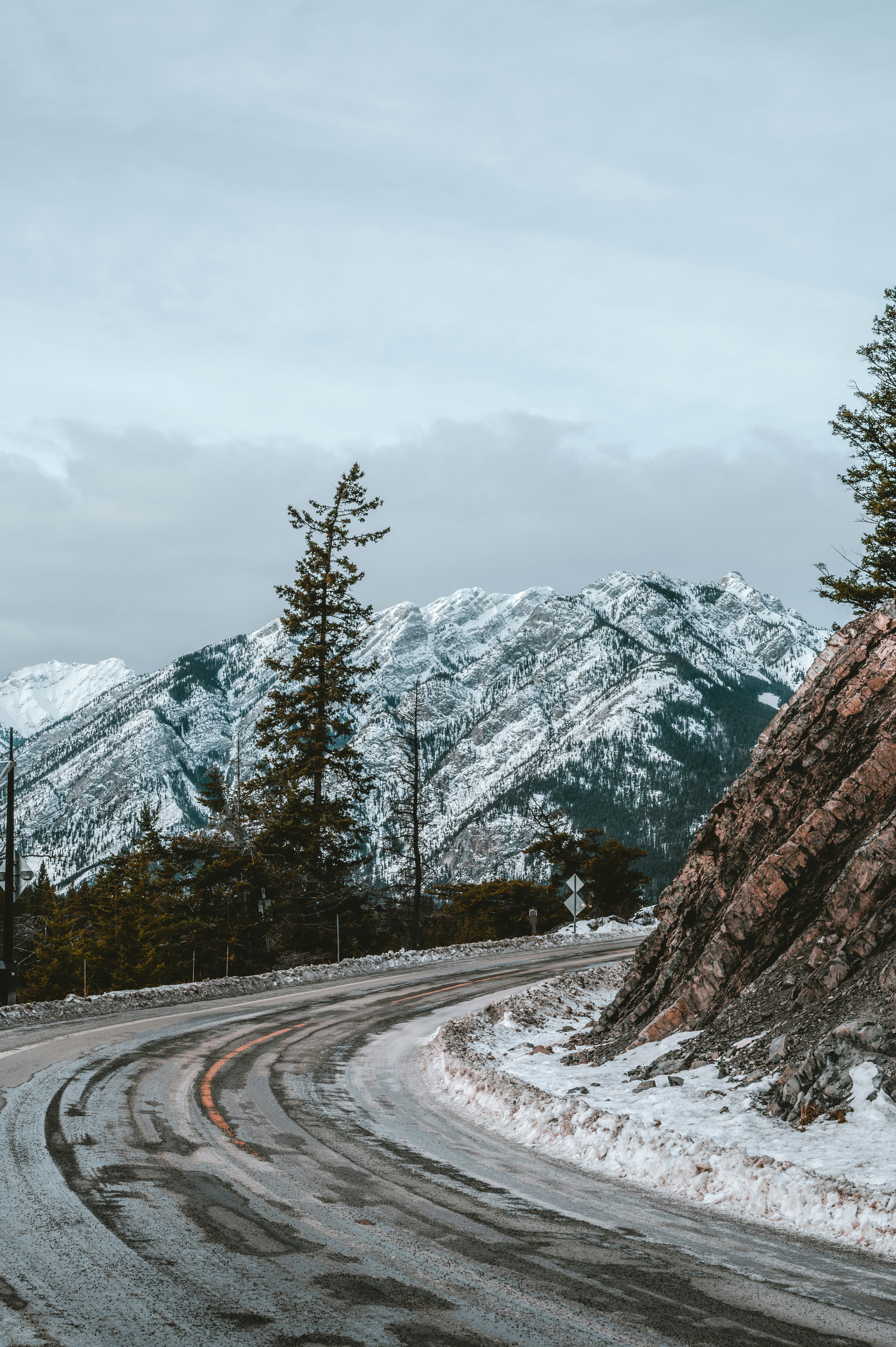 A winding road in the mountains with snow on the ground photo – Free ...