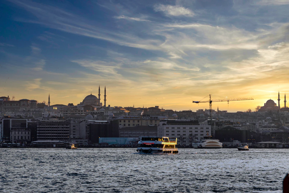 Serene cityscape at sunset with boats on water and towering mosque in background landscape