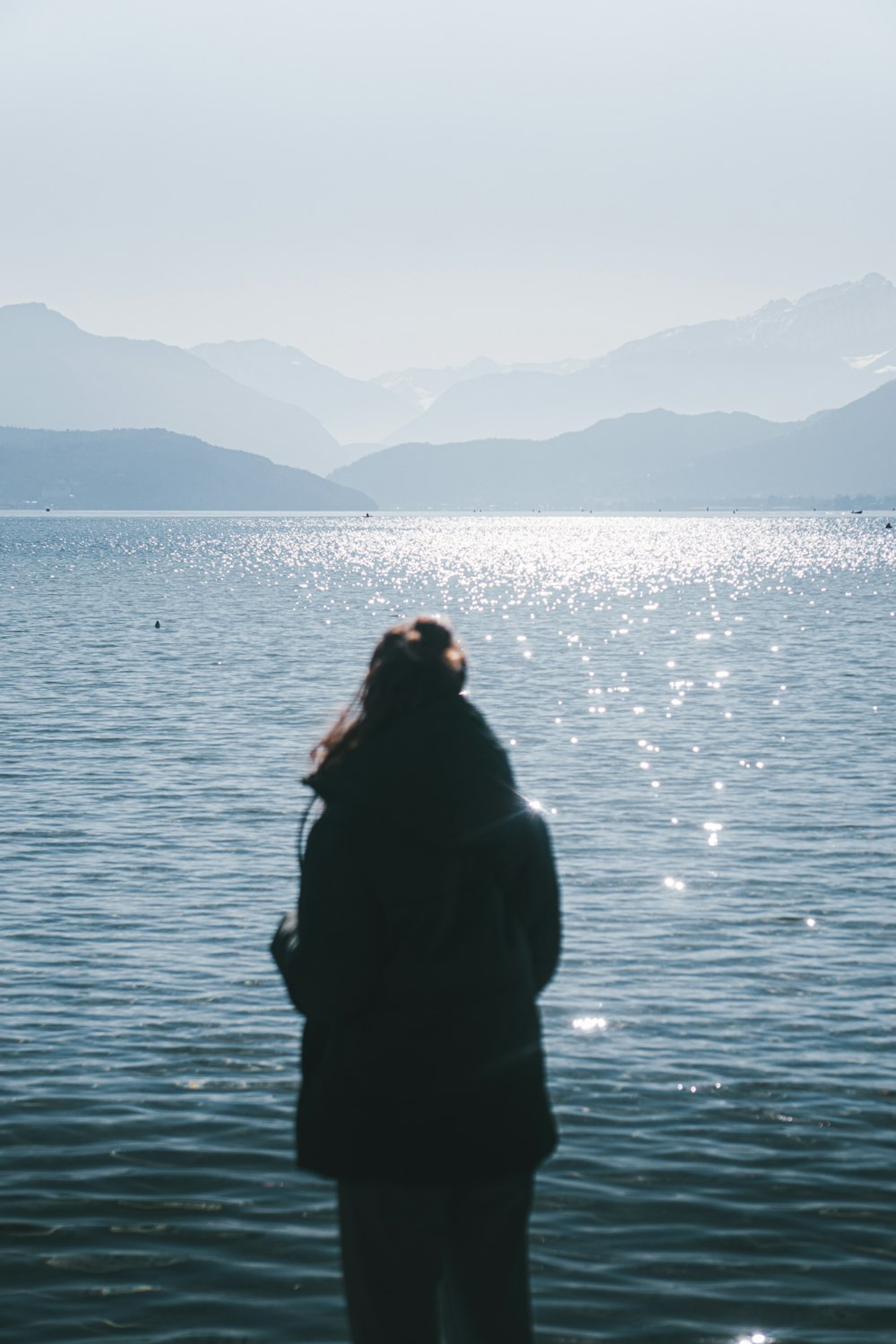 a woman standing on the edge of a body of water