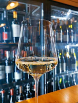 A close-up of a wine glass filled with red wine against a rustic background.