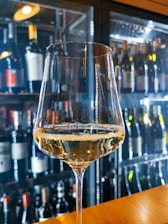 A close-up of a wine glass filled with red wine, set against a rustic wooden table.