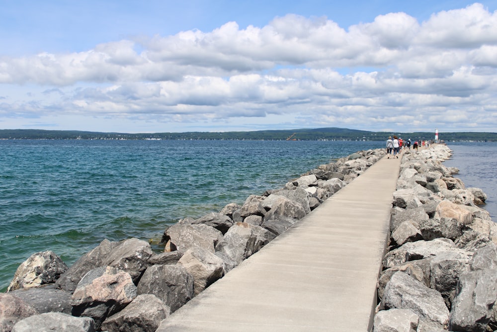 a long stone wall next to a body of water