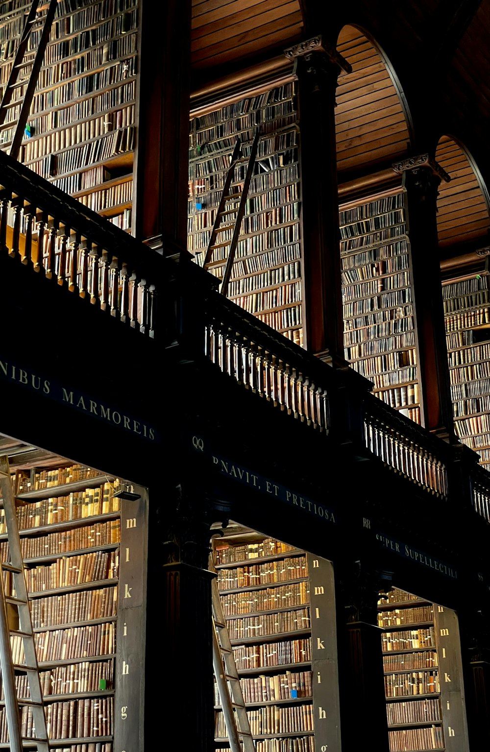 a library filled with lots of books under a wooden ceiling