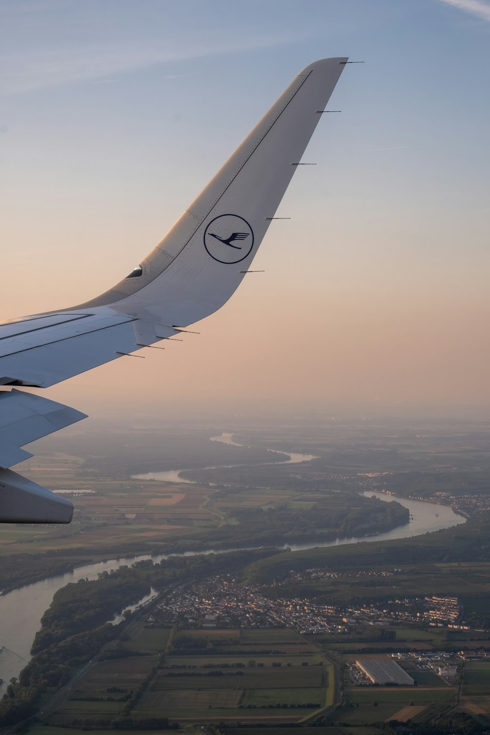 the wing of an airplane flying over a river