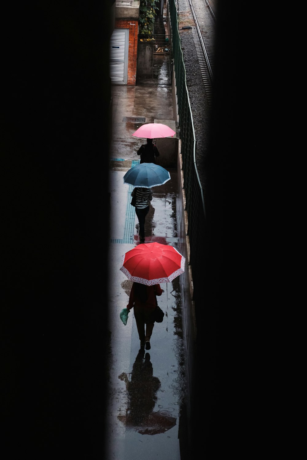 a group of people walking down a street holding umbrellas