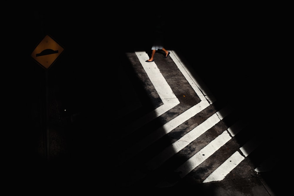 a person walking across a cross walk in the dark