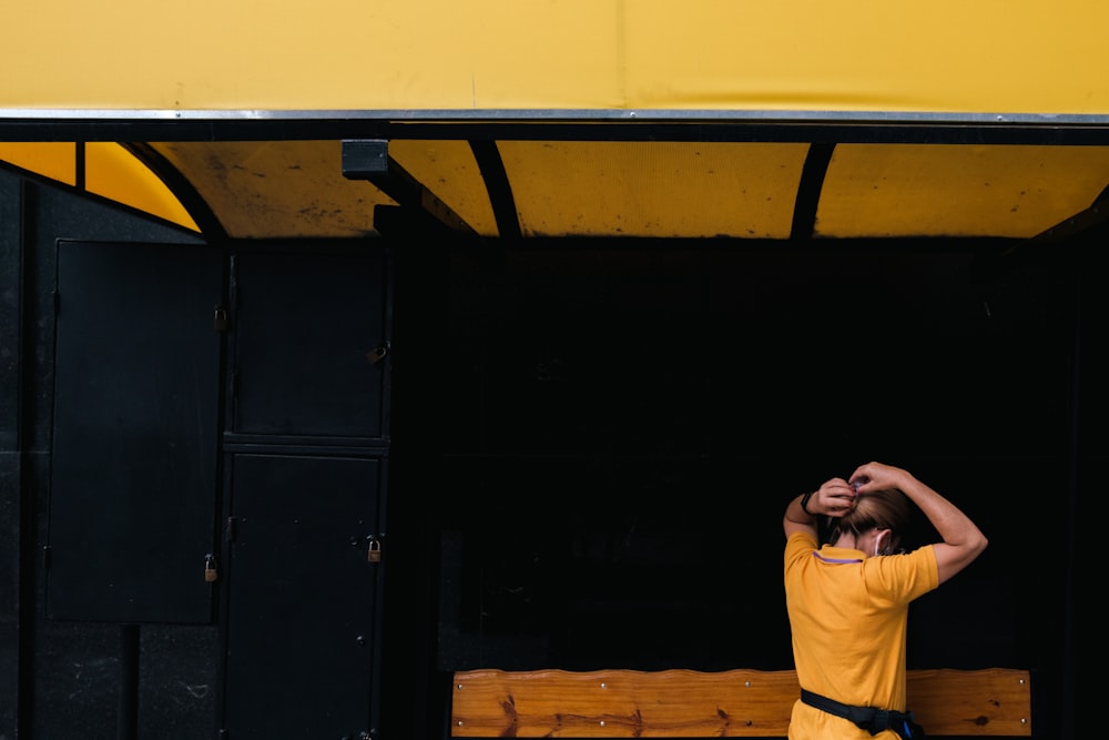 a man in a yellow shirt standing in front of a bench