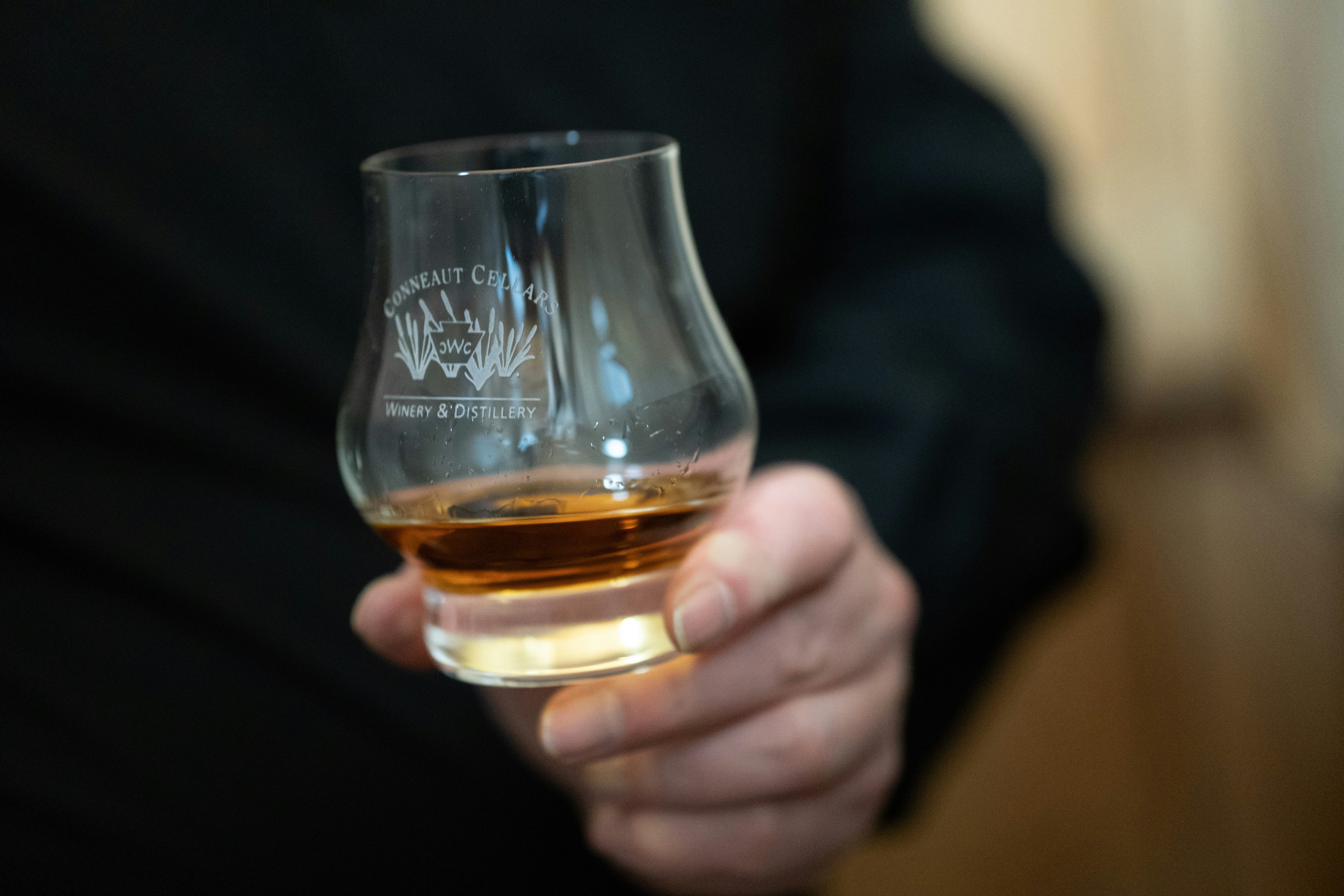 Hand holding a tasting glass of whisky