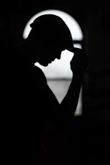 a silhouette of a man holding his head in his hands