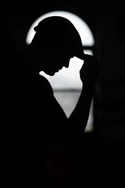 a silhouette of a man holding his head in his hands