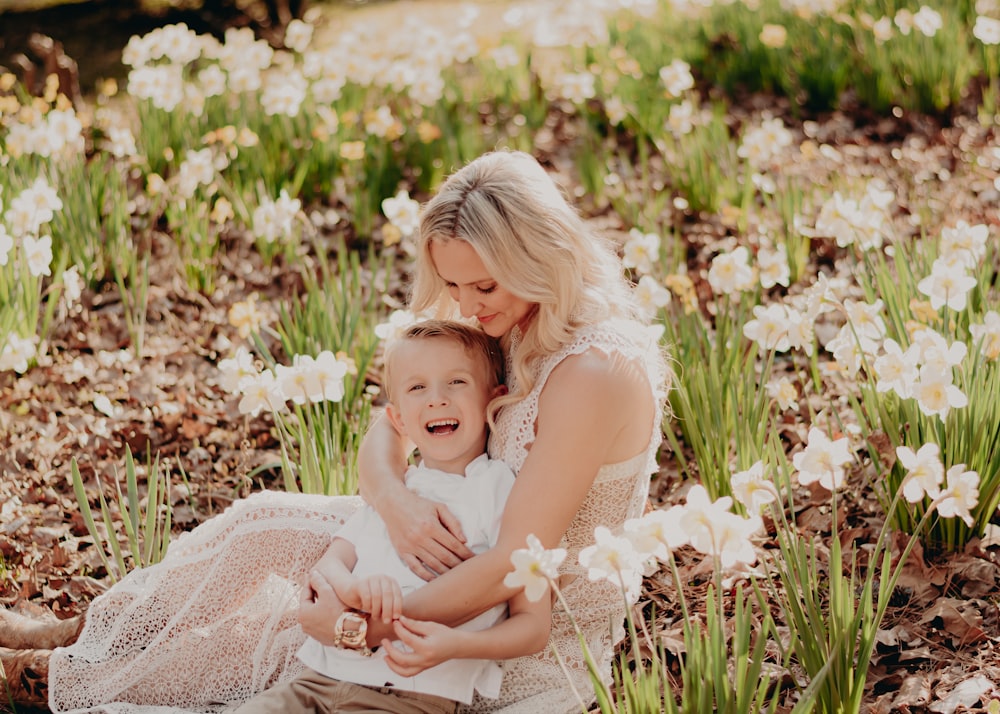 a woman and a child sitting in a field of flowers
