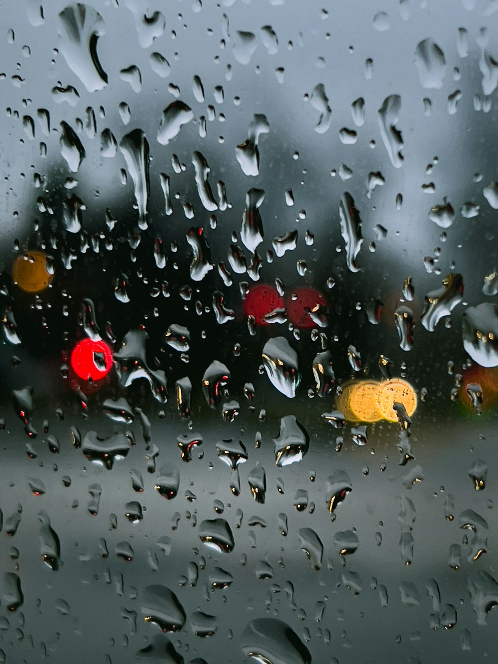 Gotas de lluvia en una ventana con semáforos de fondo