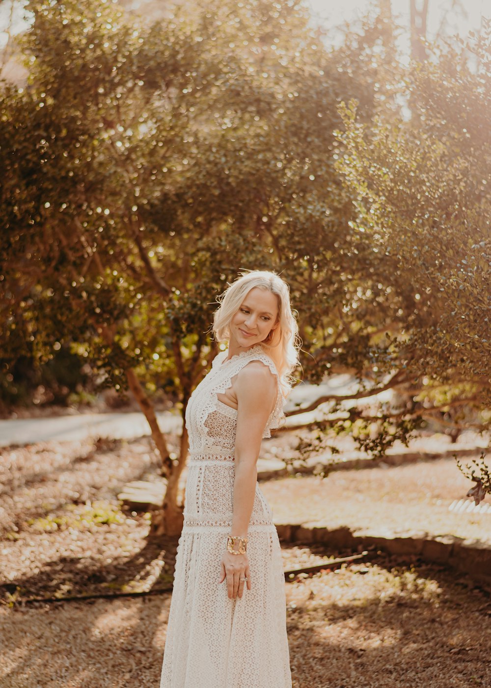 Una mujer con un vestido blanco parada frente a un árbol