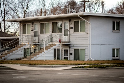 a two story white building with stairs leading up to it