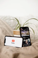 a cell phone sitting on top of a bed next to a plant