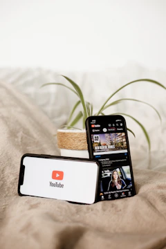 a cell phone sitting on top of a bed next to a plant