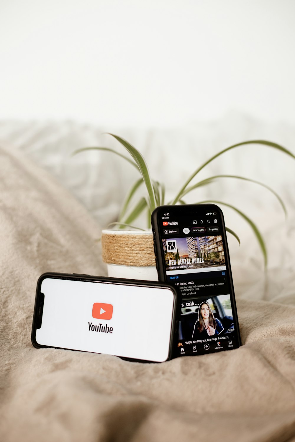 a cell phone sitting on top of a bed next to a plant