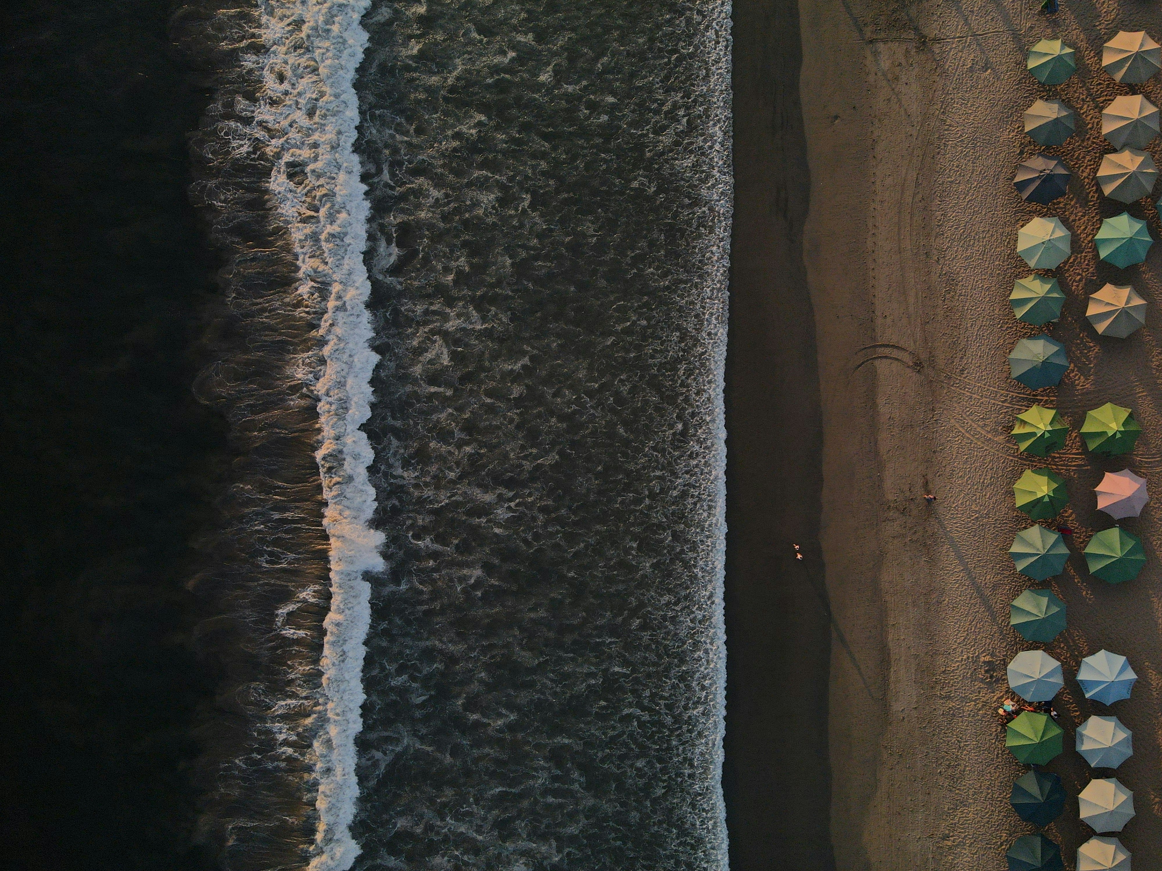 an aerial view of a beach with umbrellas