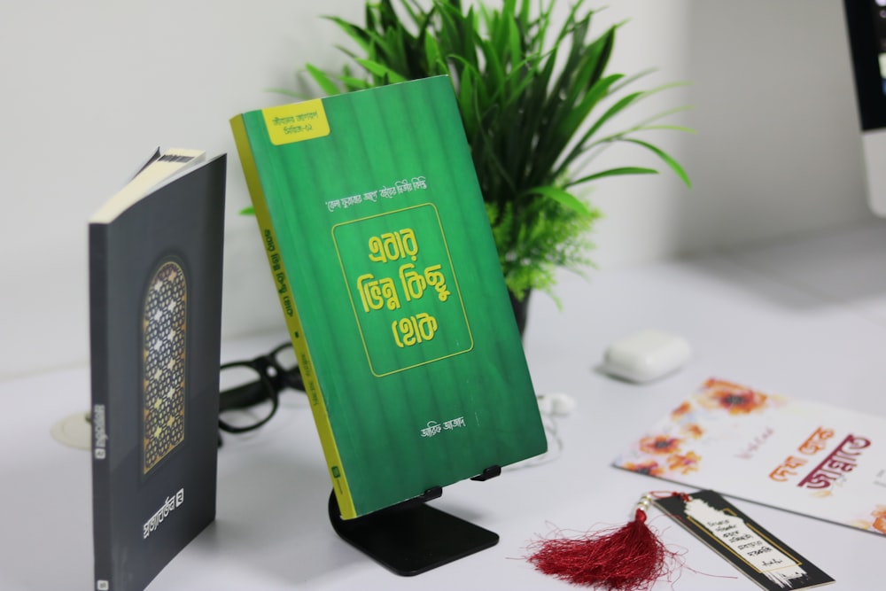 a green book sitting on top of a table next to a plant