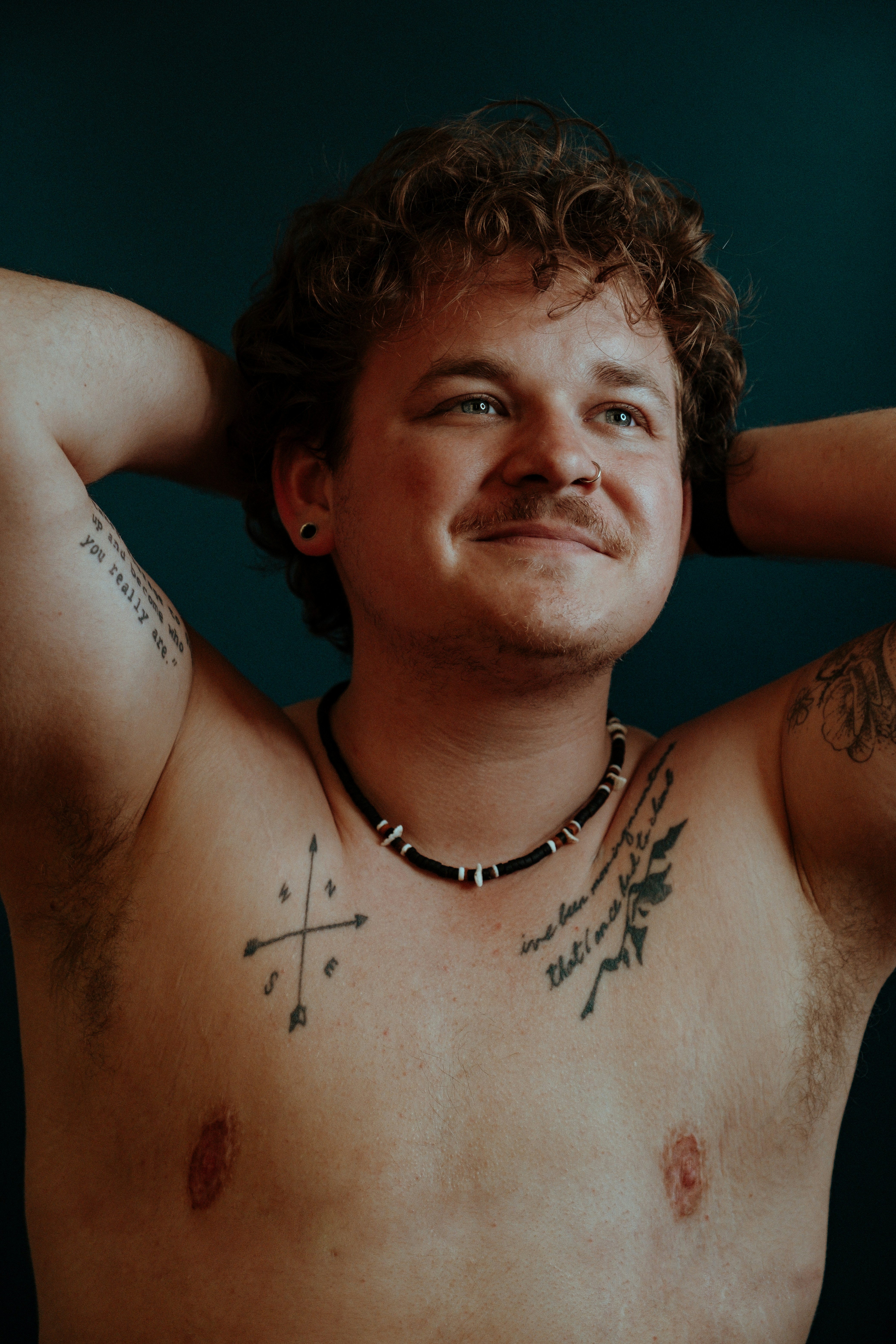 a man with tattoos on his chest posing for a picture