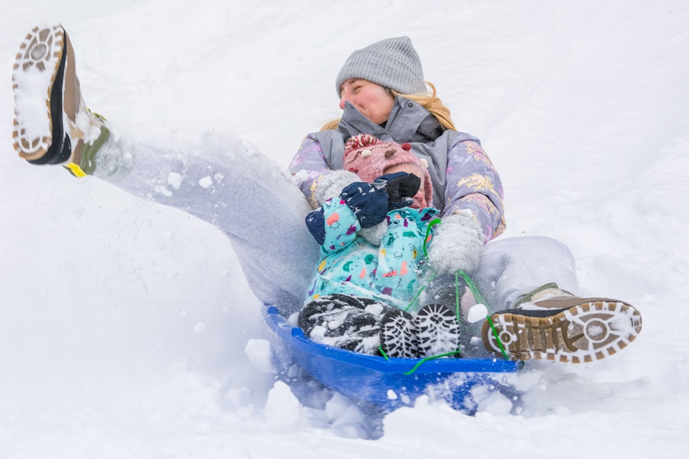 a woman riding a sled down a snow covered slope