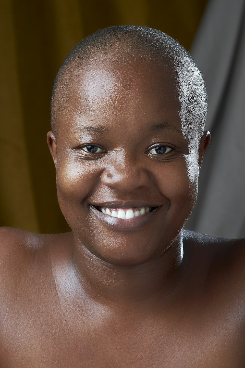 uma mulher negra com a cabeça raspada sorrindo