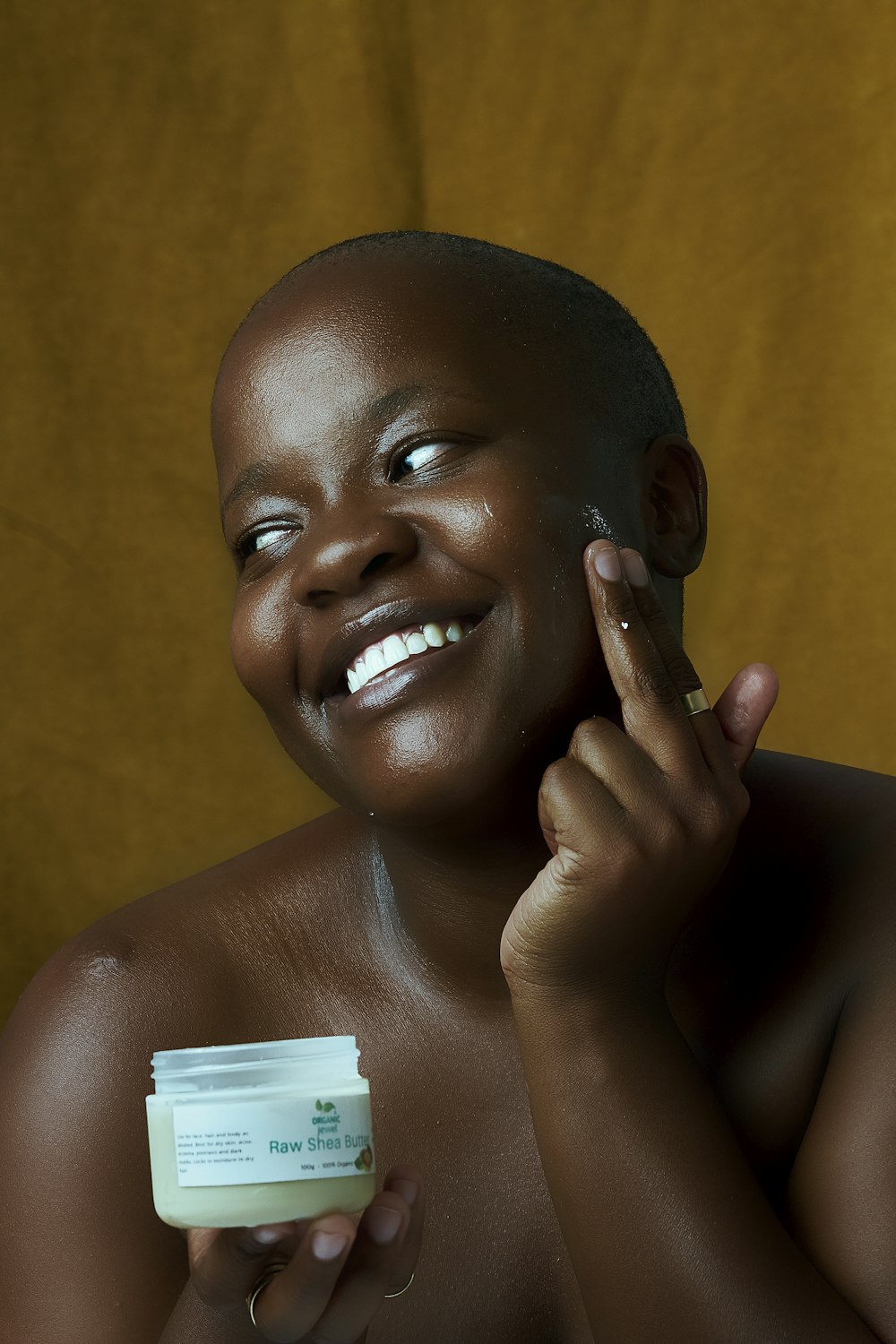 a woman smiles while holding a container of cream