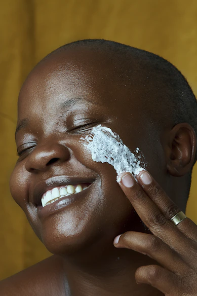 a woman is applying body butter to her face