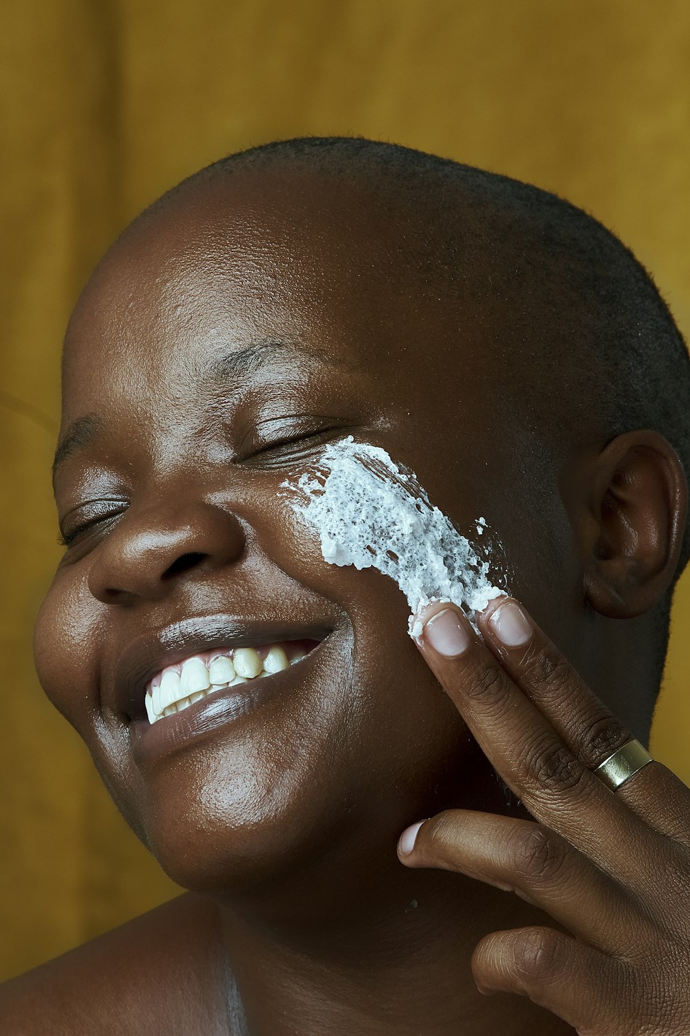 a woman is smiling and holding a piece of white powder on her face