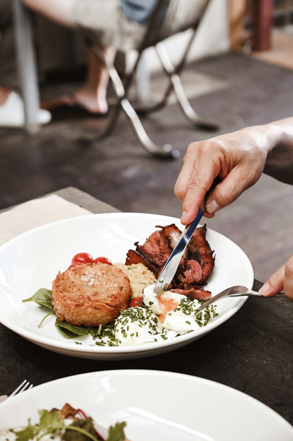 a person cutting a piece of meat on top of a white plate