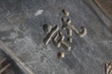 Stone or metal characters are carved into a textured surface, possibly part of an old sign or monument. The material has a slightly weathered appearance, suggesting age or exposure to the elements.