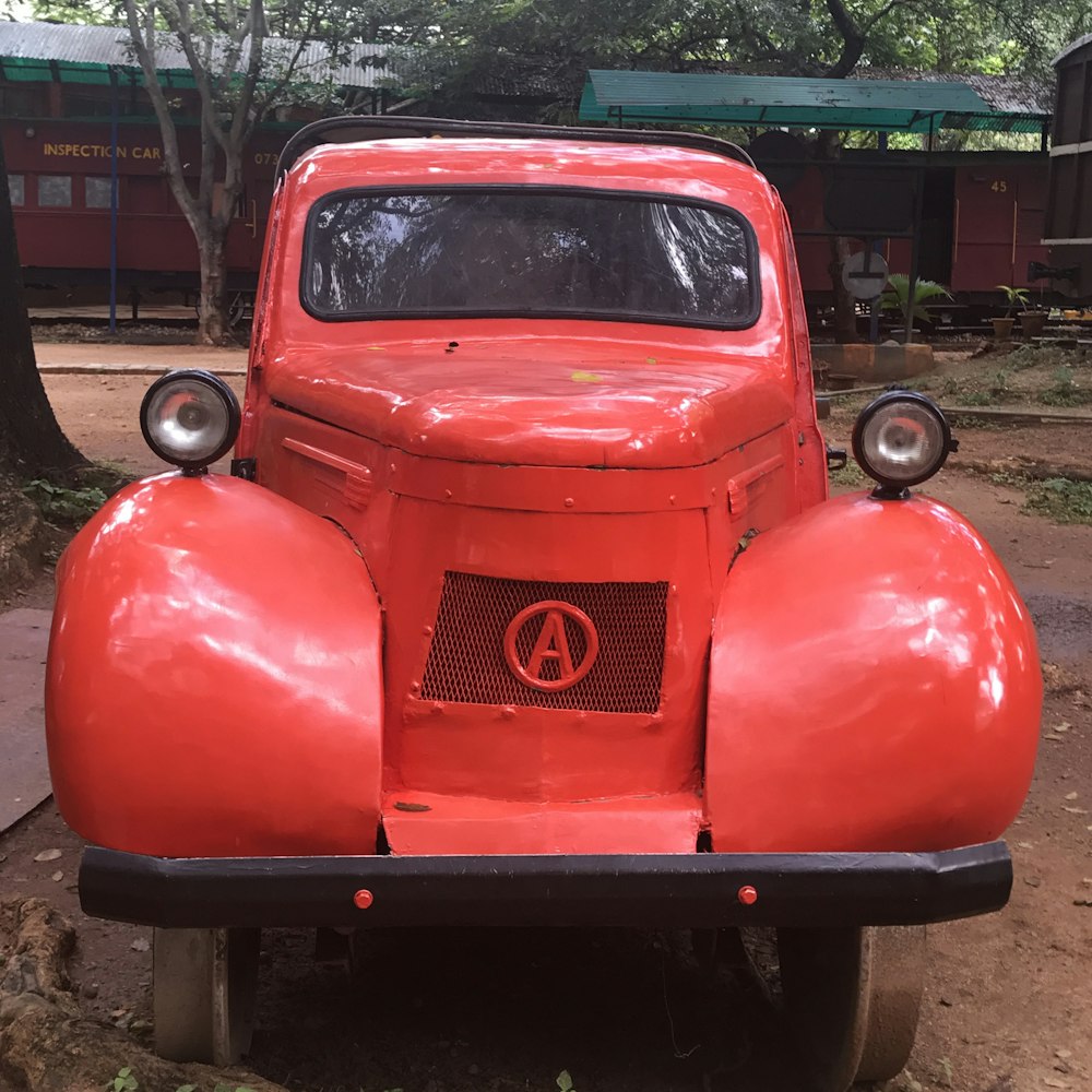 an old red truck parked on a dirt road