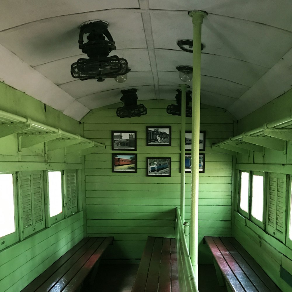 a green room with wooden benches and pictures on the wall