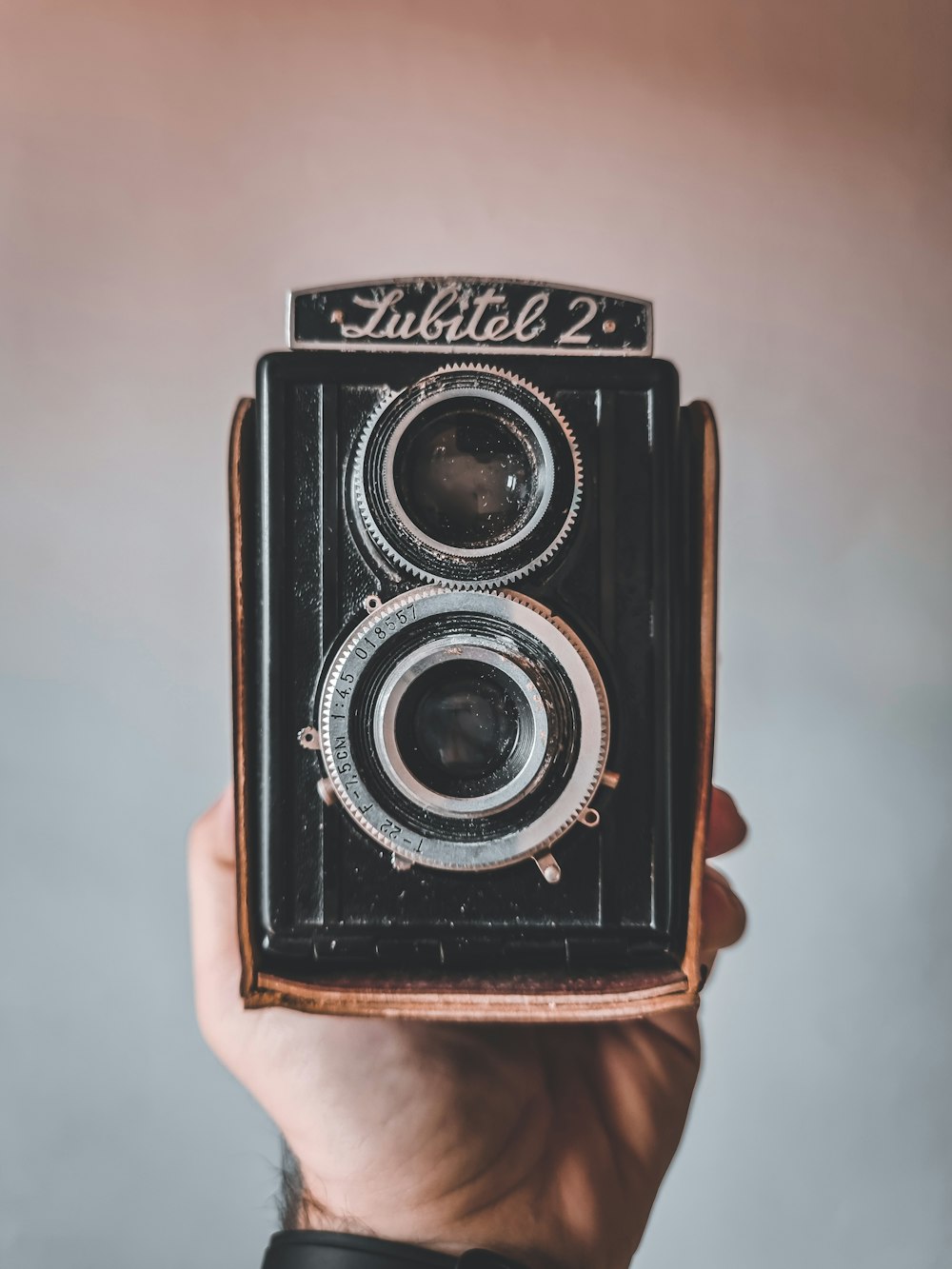 a person holding up an old fashioned camera